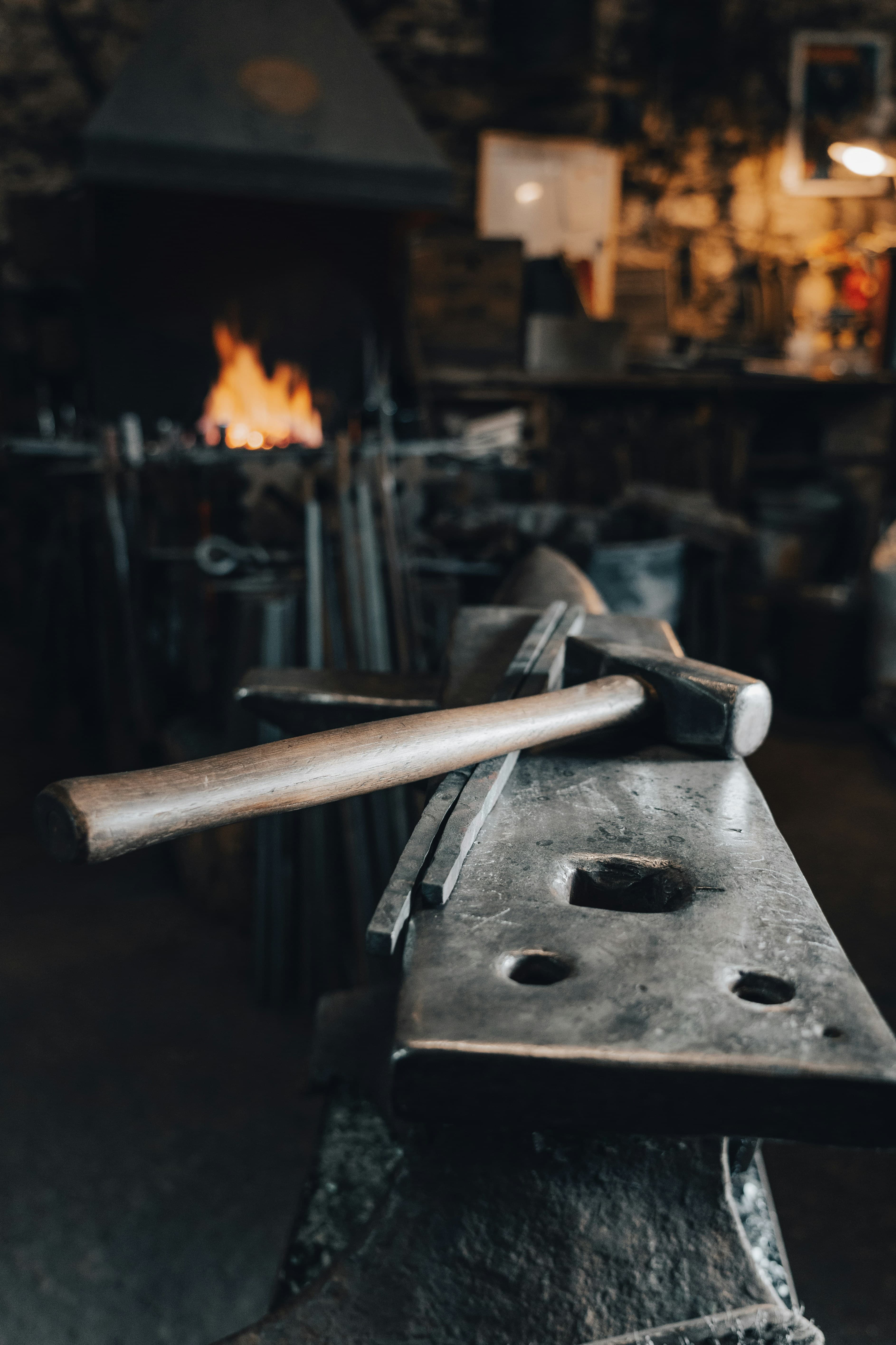 A working forge: hammer resting on the anvil, fire glowing in the hearth